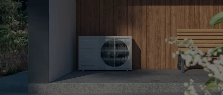 Wärmepumpenanlage neben einer Holzwand im Außenbereich eines modernen Gebäudes.