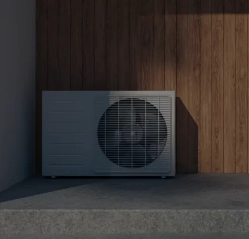 Wärmepumpenanlage neben einer Holzwand im Außenbereich eines modernen Gebäudes.